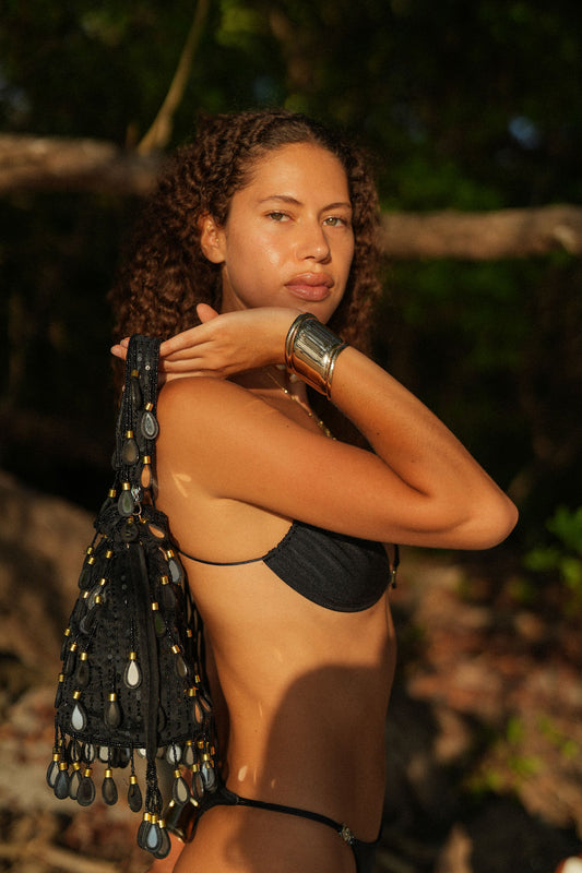 Woman wearing Black Elio velvet bucket bag with obsidian mirror drops and pearl glass fringe, handcrafted statement accessory